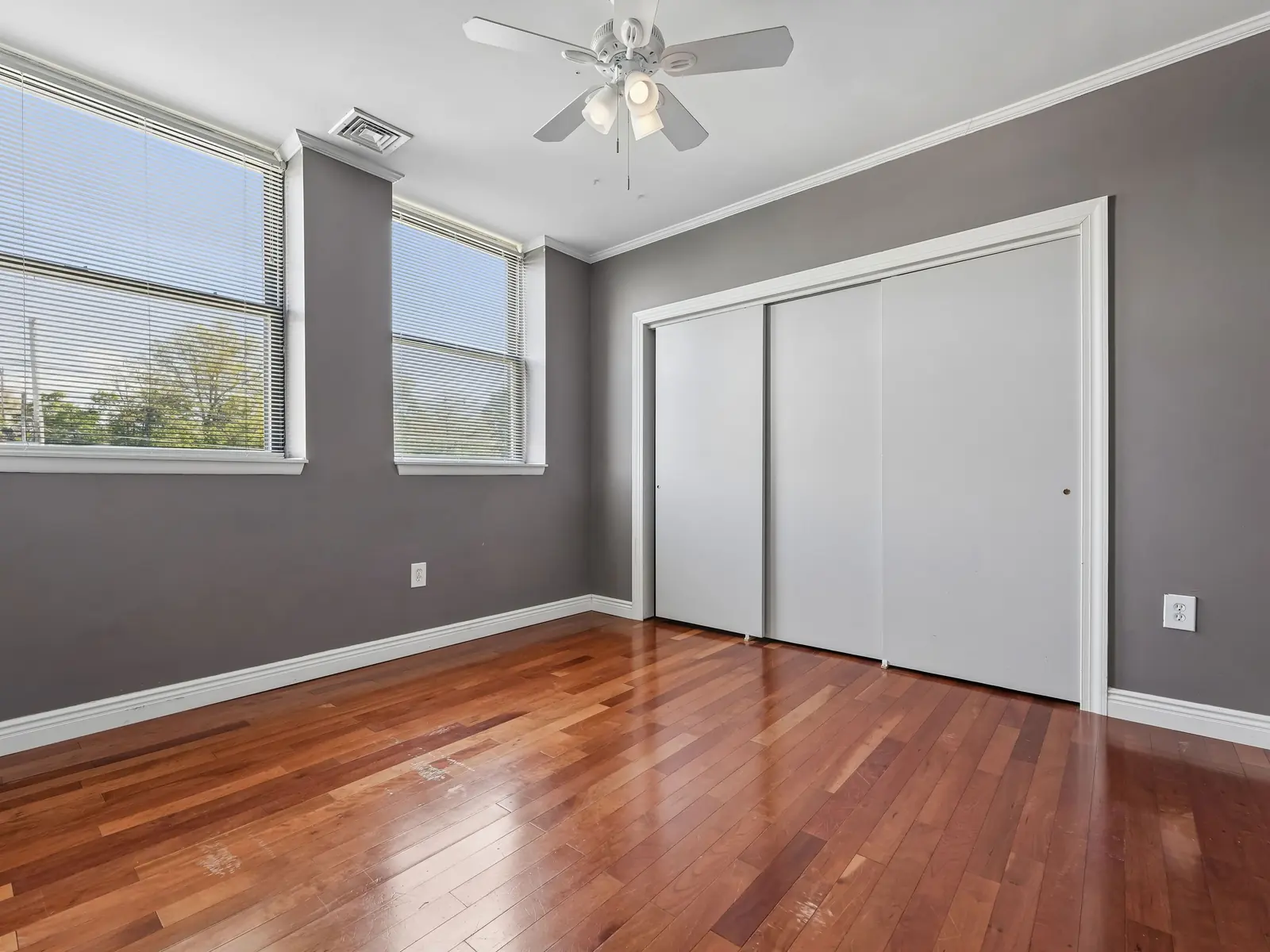 Spacious primary bedroom with two windows, hardwood floors, ceiling fan, and double sliding closets at School House Plaza Denville