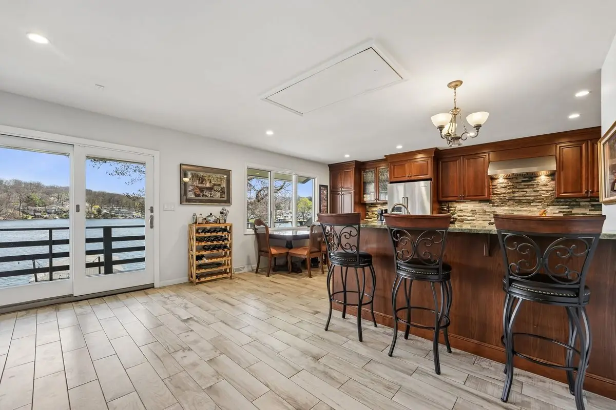 Open kitchen and dining area with a raised breakfast bar, swivel stools, chandelier, and sliding doors framing Lake Hopatcong views at 213 Hudson Avenue