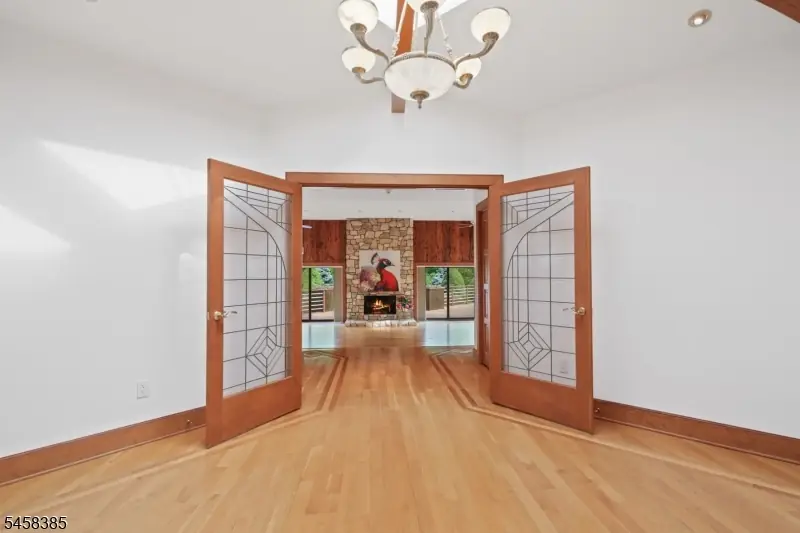 Leaded-glass french doors opening from the foyer into the great room, framing the floor-to-ceiling stone fireplace beyond at the Blairstown estate